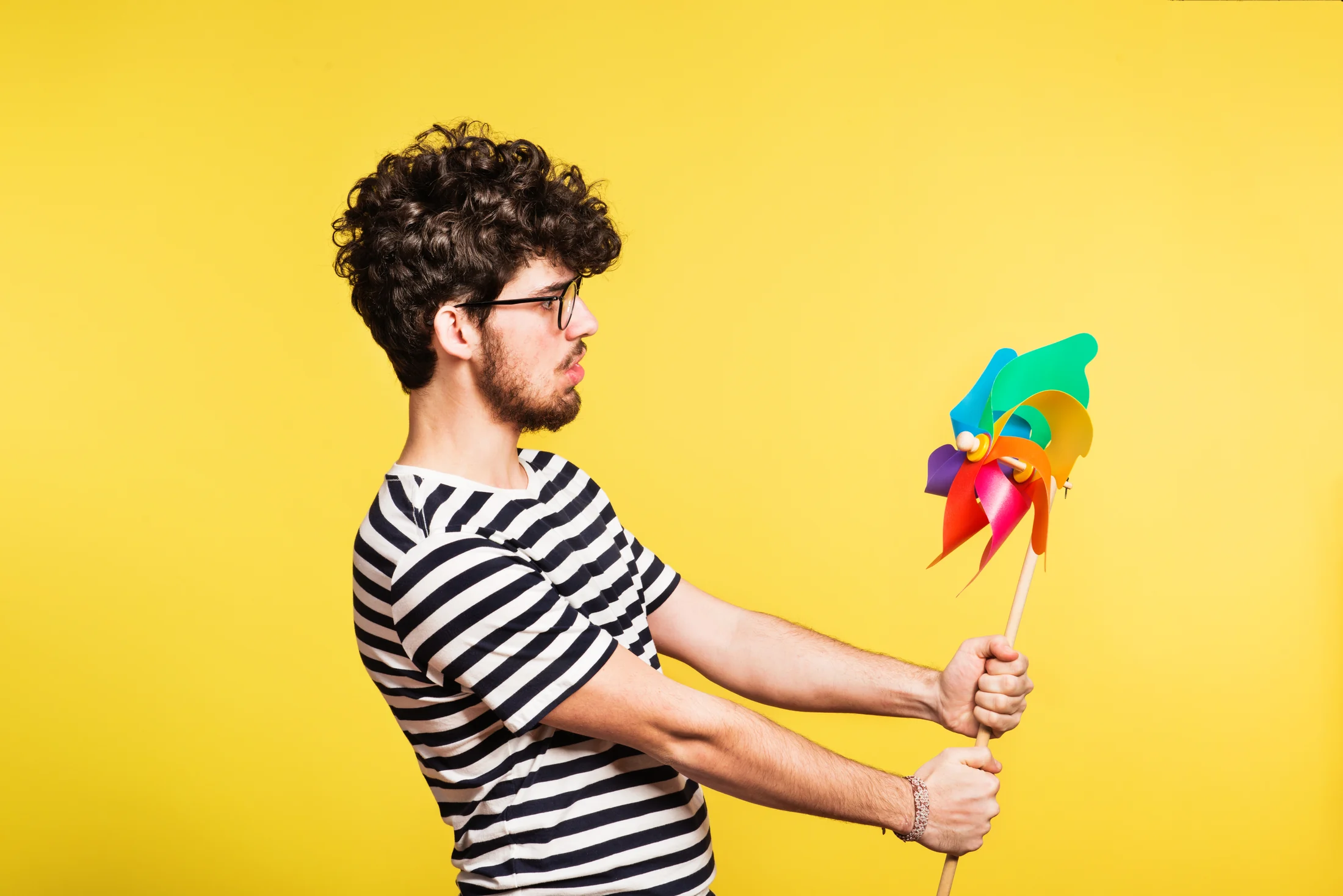 Man arranging colourful paper shapes against a yellow background