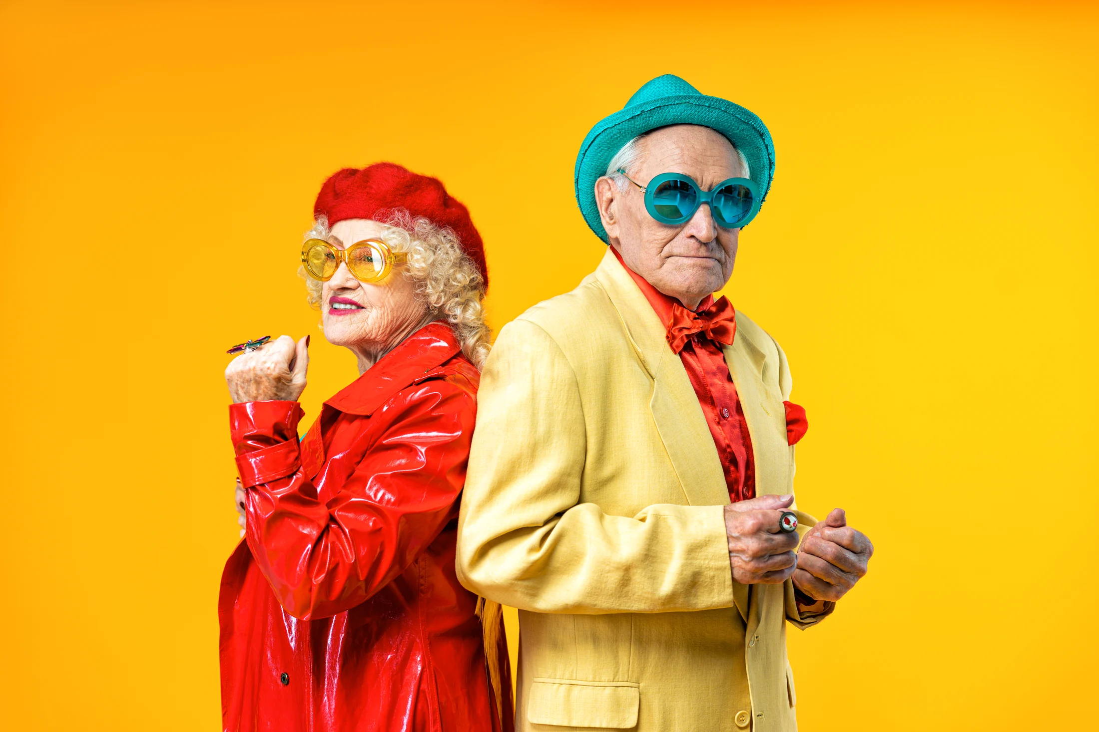 Two people in colourful suits standing back to back against yellow
