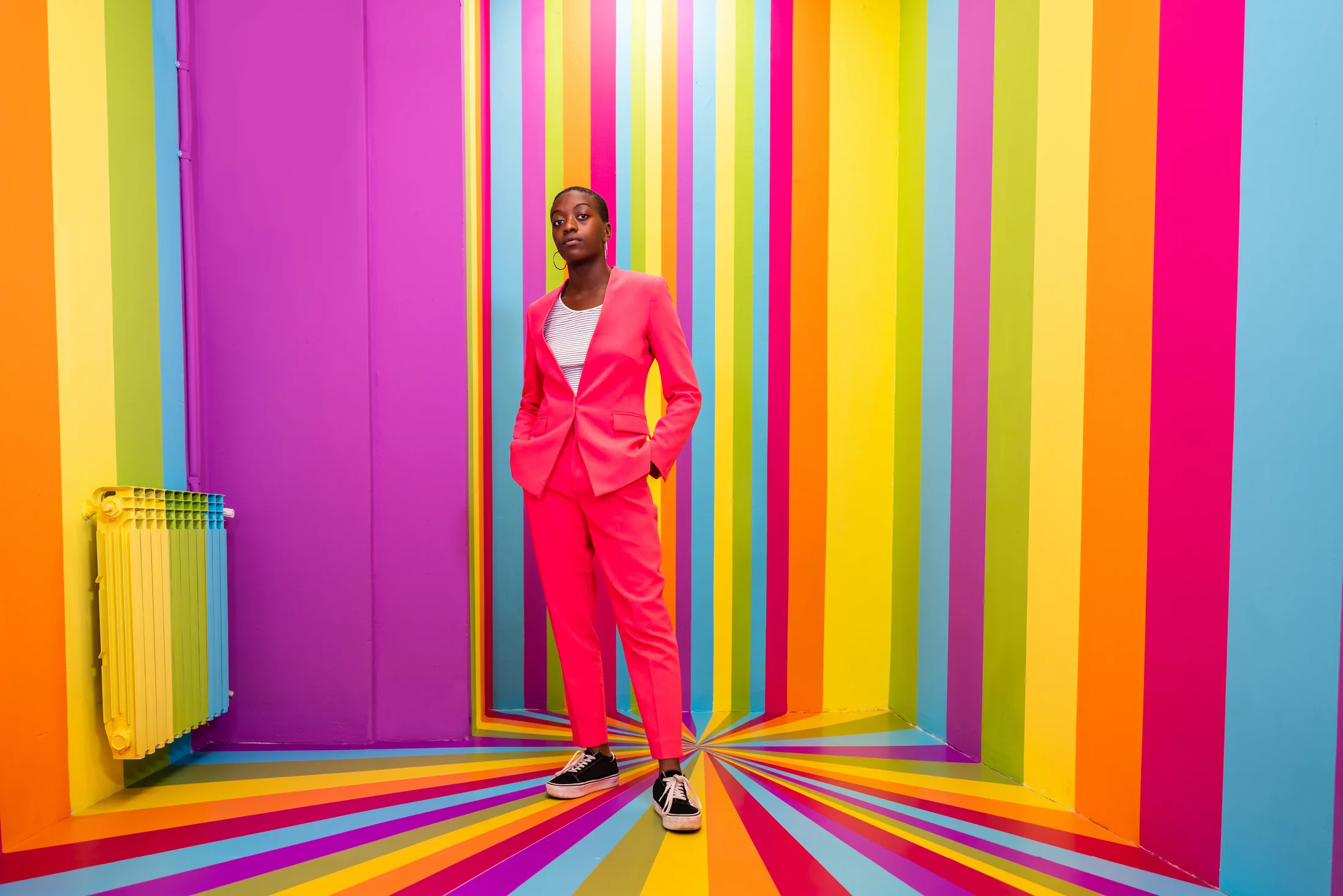 Woman standing among bold vertical bands of colour Woman standing among bold vertical bands of colour