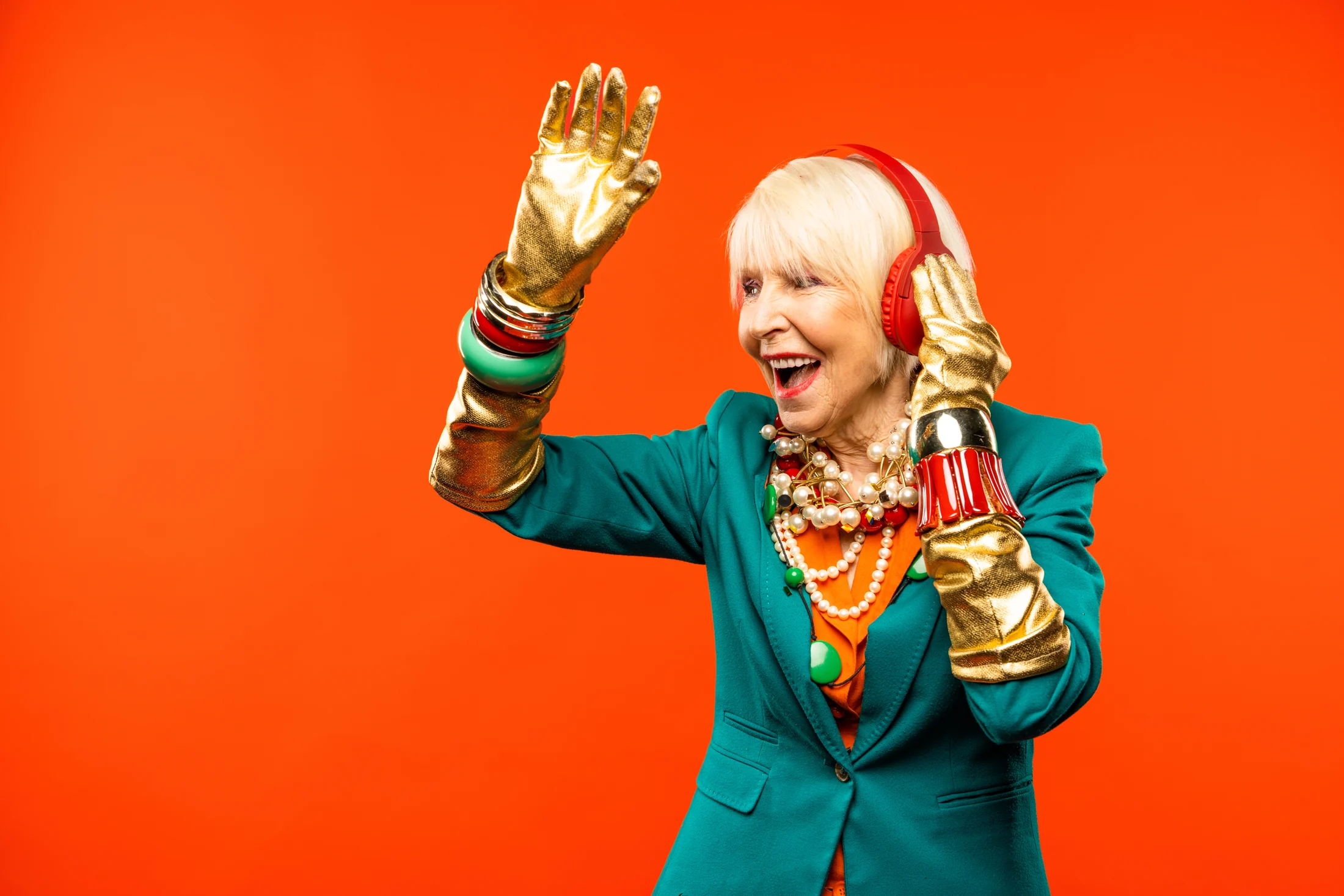 Woman in a green jacket raising her gold-gloved hands against an orange background Woman in a green jacket raising her gold-gloved hands against an orange background