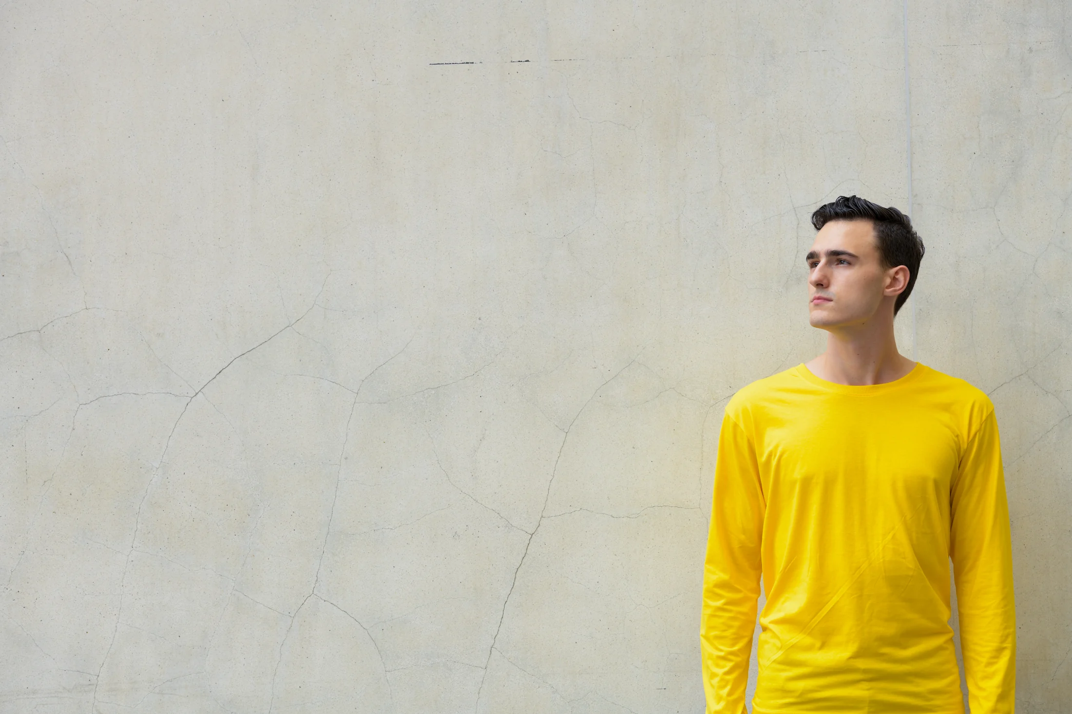 Man in a yellow top looking across an open grey background