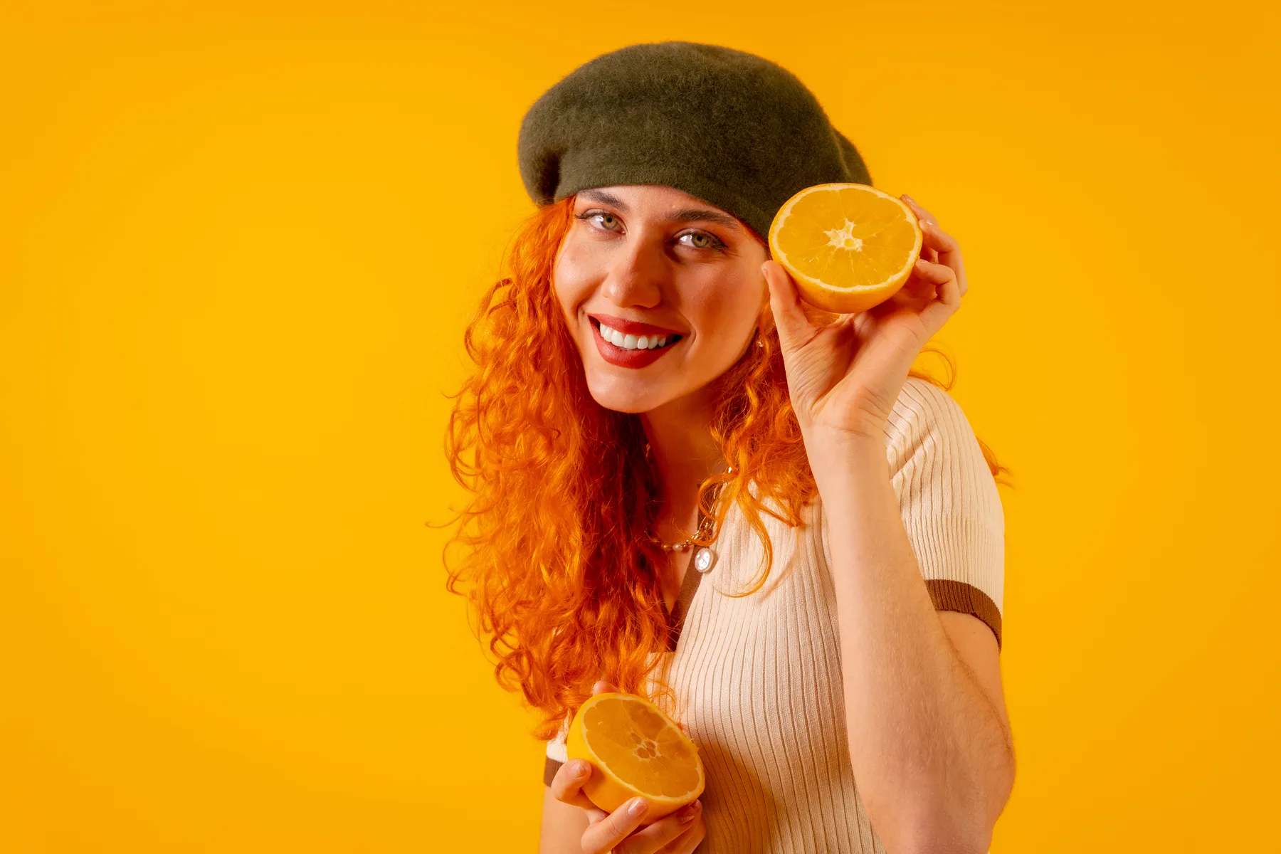 Smiling Woman Holds Orange Halves on Yellow Backdrop
