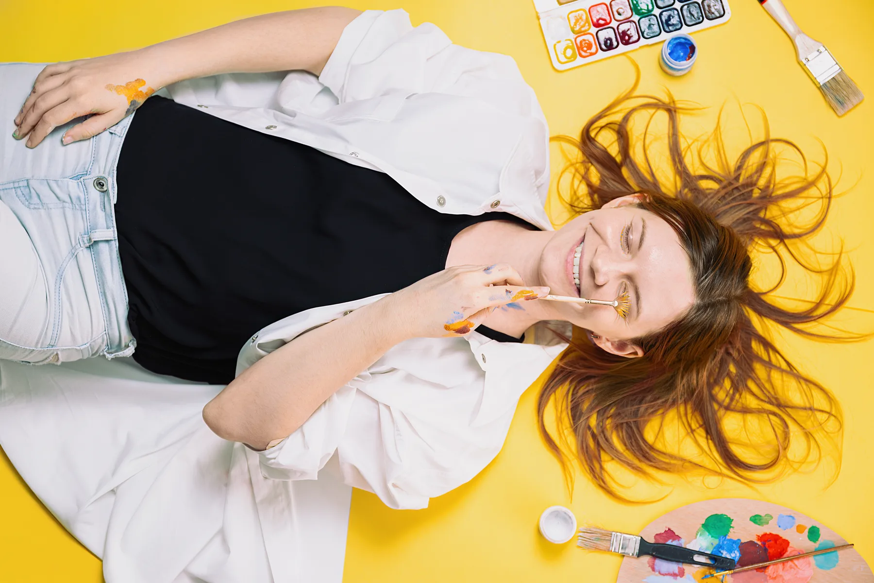 Woman with Paintbrush, Lying on Yellow Background Woman with Paintbrush, Lying on Yellow Background