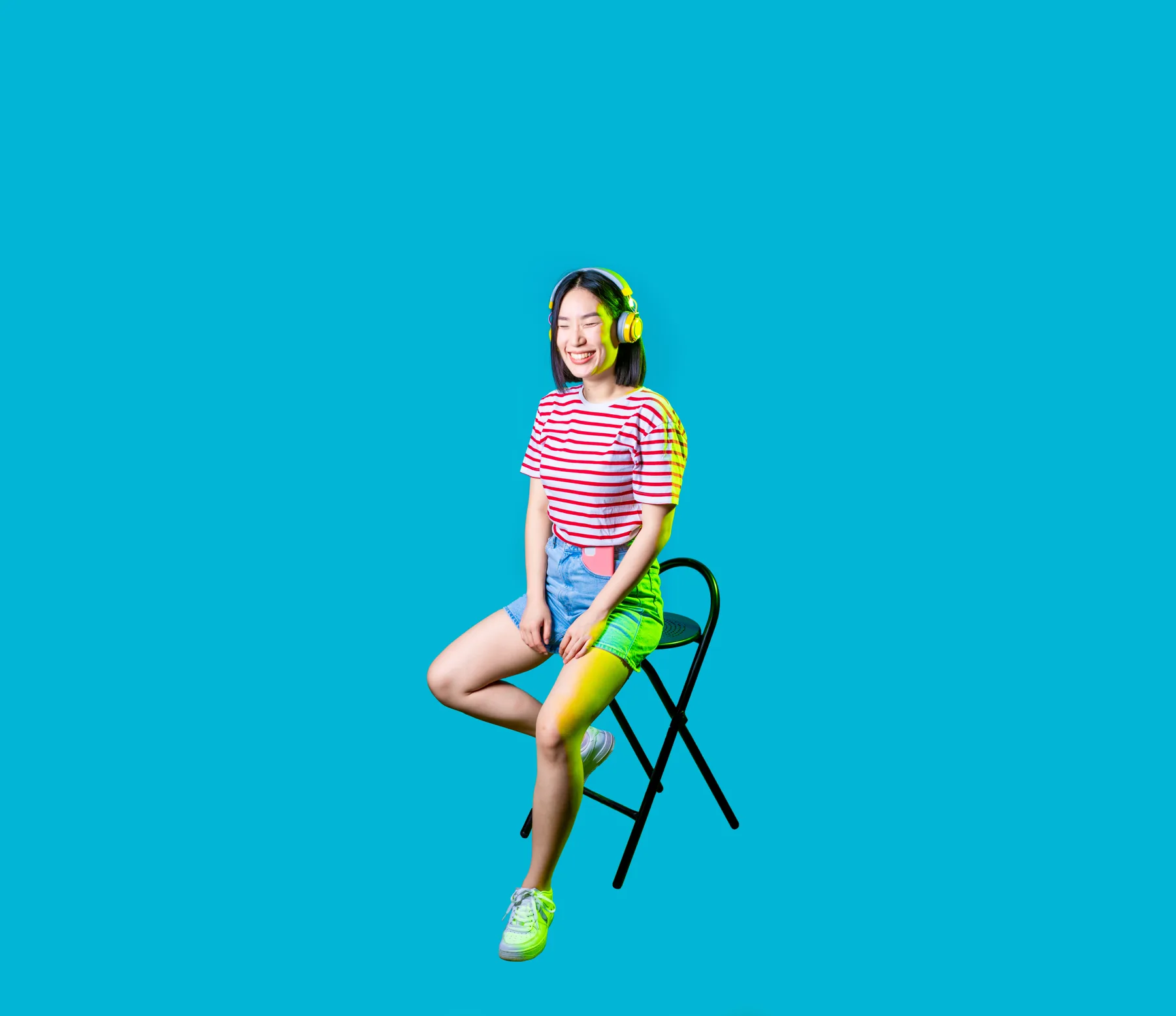 Young Woman With Headphones On Chair, Light Background