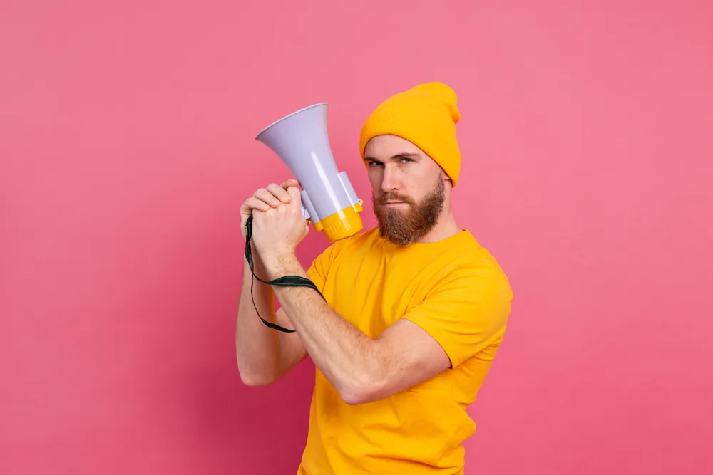 Man in Yellow with a Megaphone Against Pink