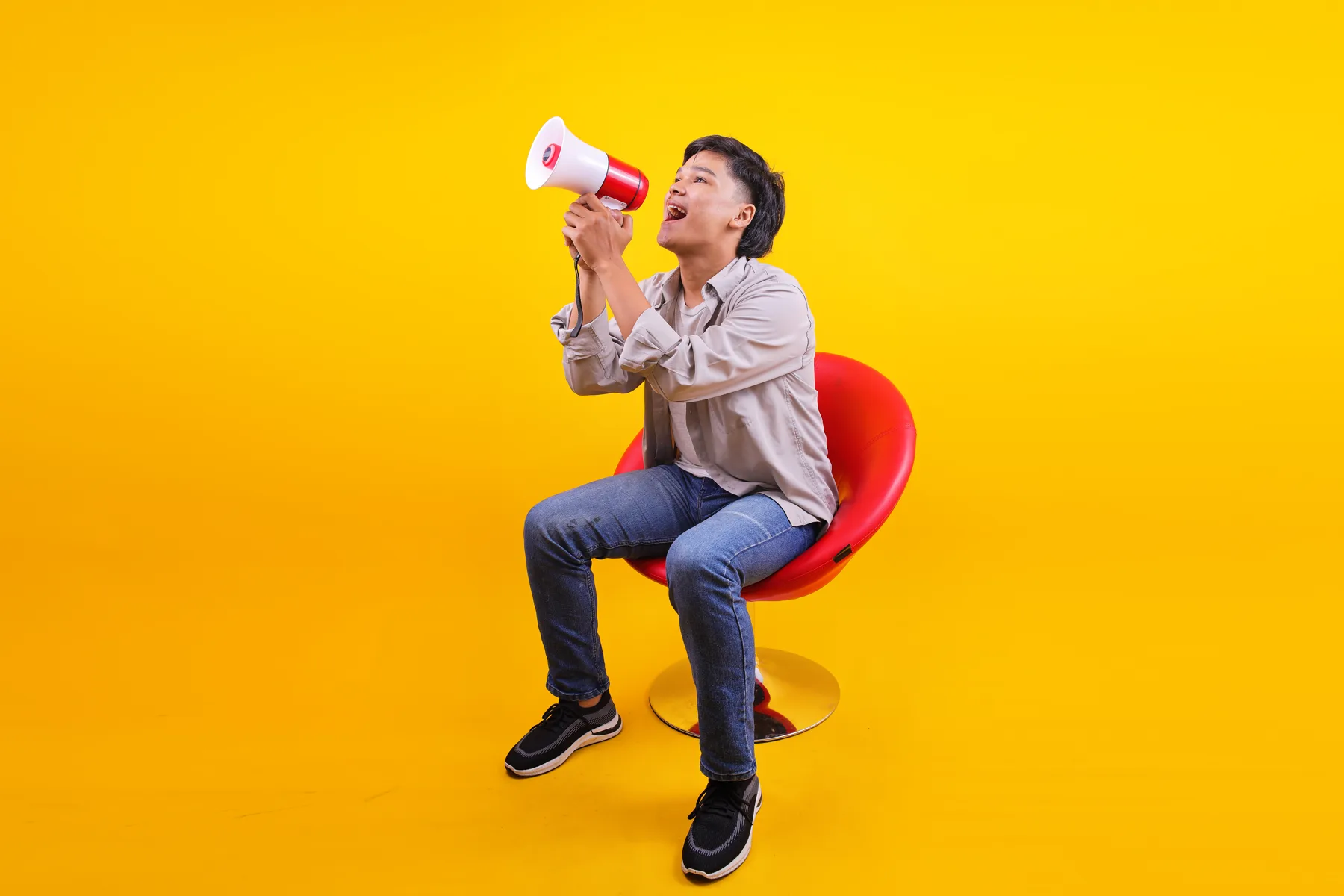 Excited Man Sitting and Speaking Into Megaphone
