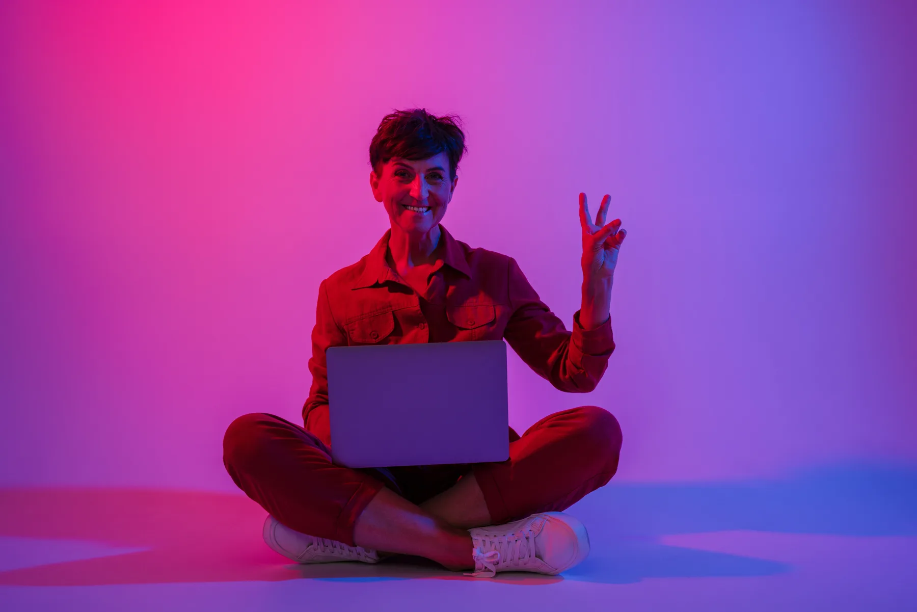 Woman Doing Peace Sign with Laptop in Studio Woman Doing Peace Sign with Laptop in Studio