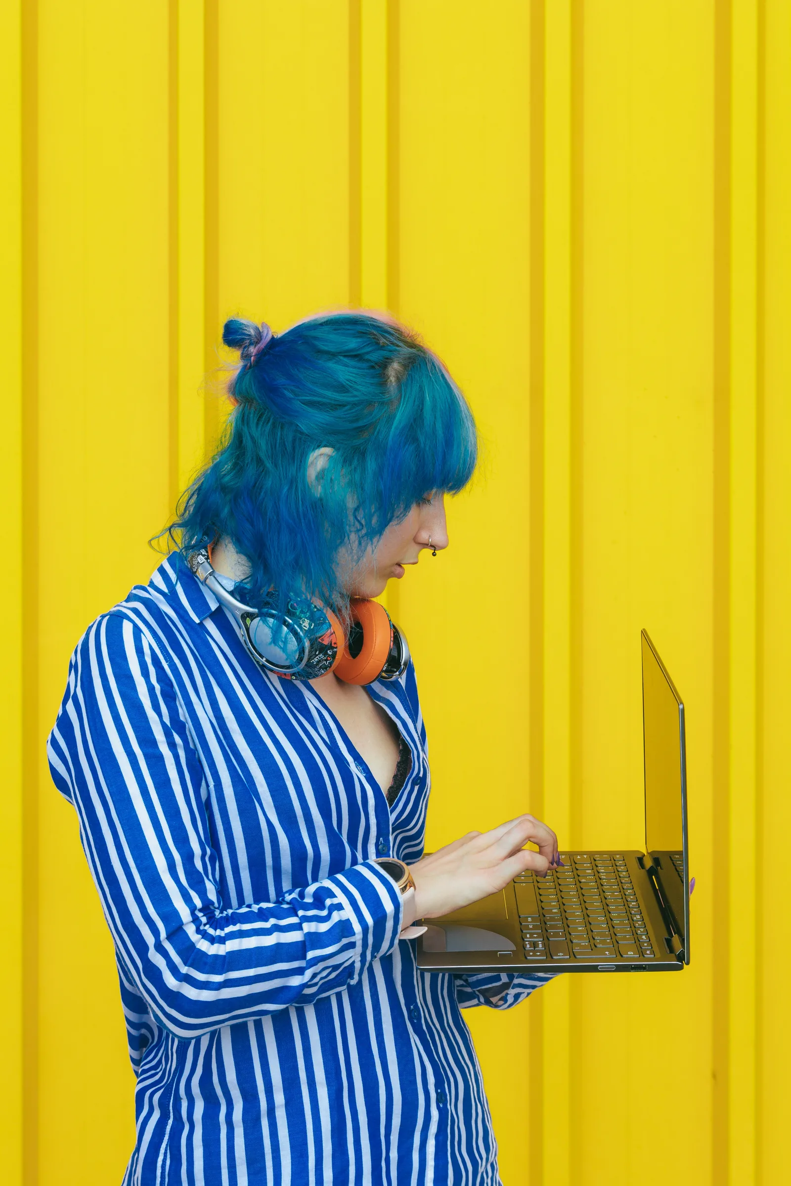 Stylish Person Working on a Laptop Near Yellow Wall Stylish Person Working on a Laptop Near Yellow Wall