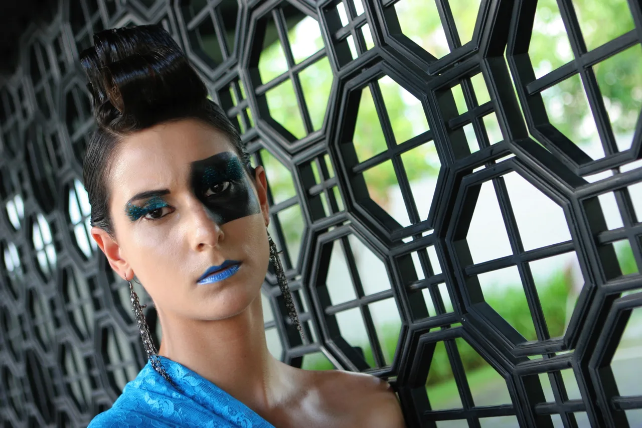 Fashion portrait with blue styling behind an architectural geometric screen
