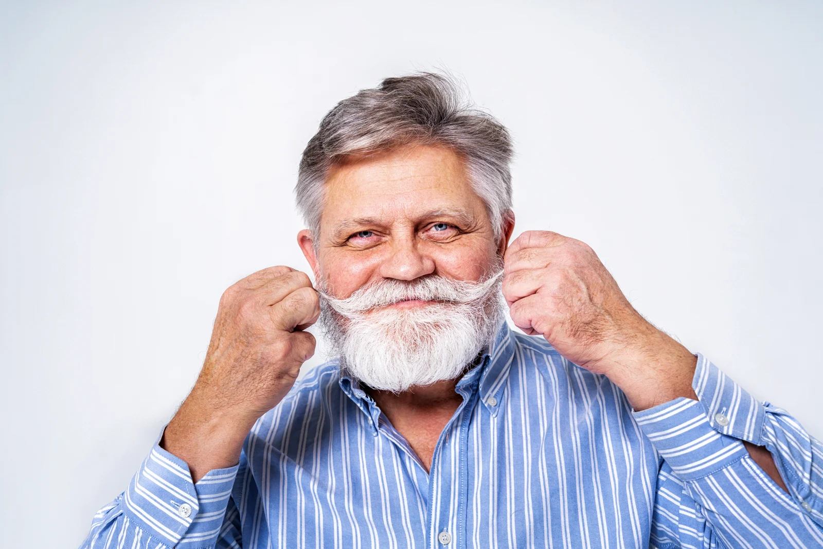 Older man playfully smiling with his moustache