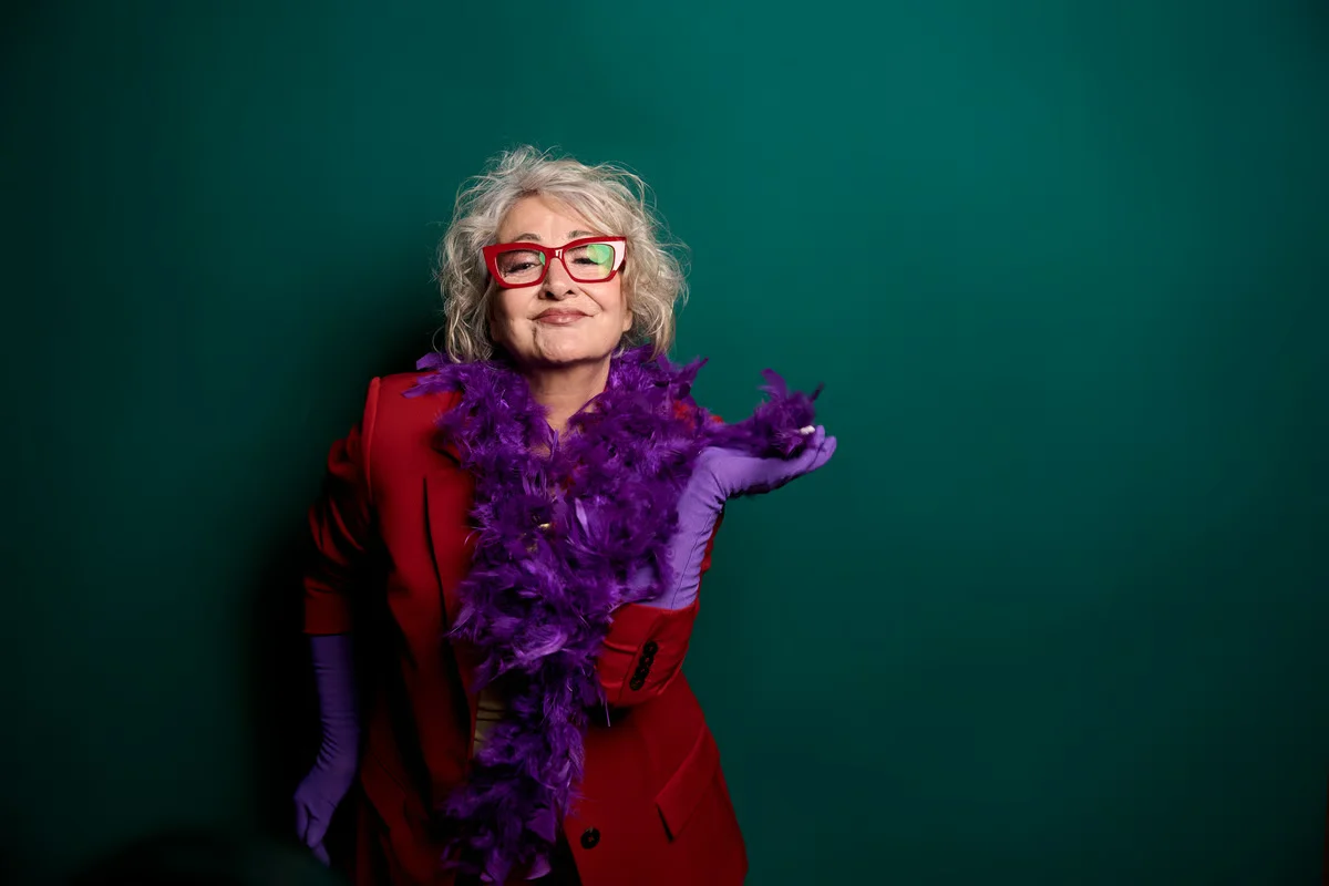 Expressive senior woman in a red blazer and purple boa